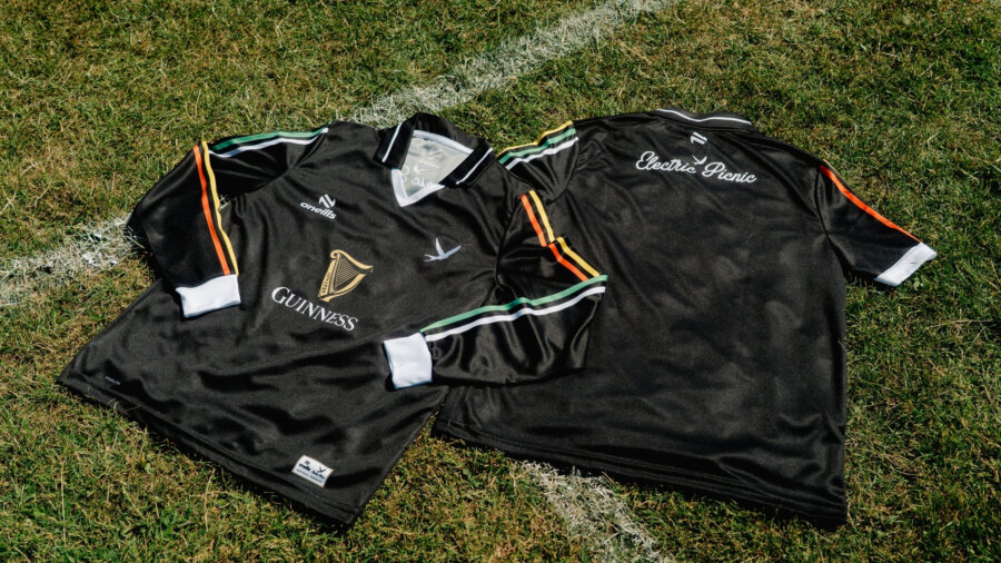 a picture of two black gaa football jerseys on a grass football pitch with white lines marking the grass